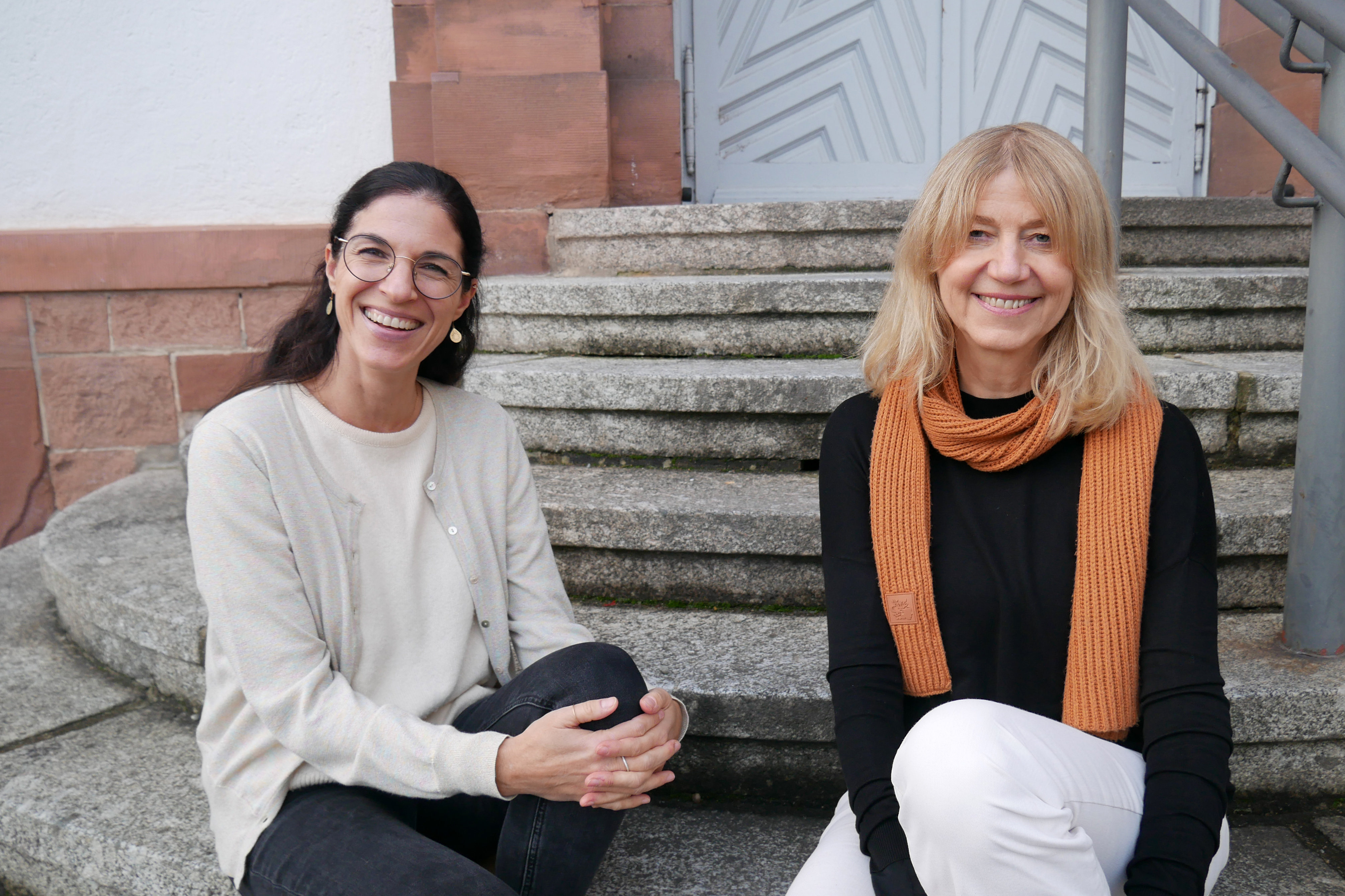 Fachrichtung Hören Die beiden Ausbilderinnen der Fachrichtung Hören sitzen auf der Steintreppe am Eingang des Seminars.