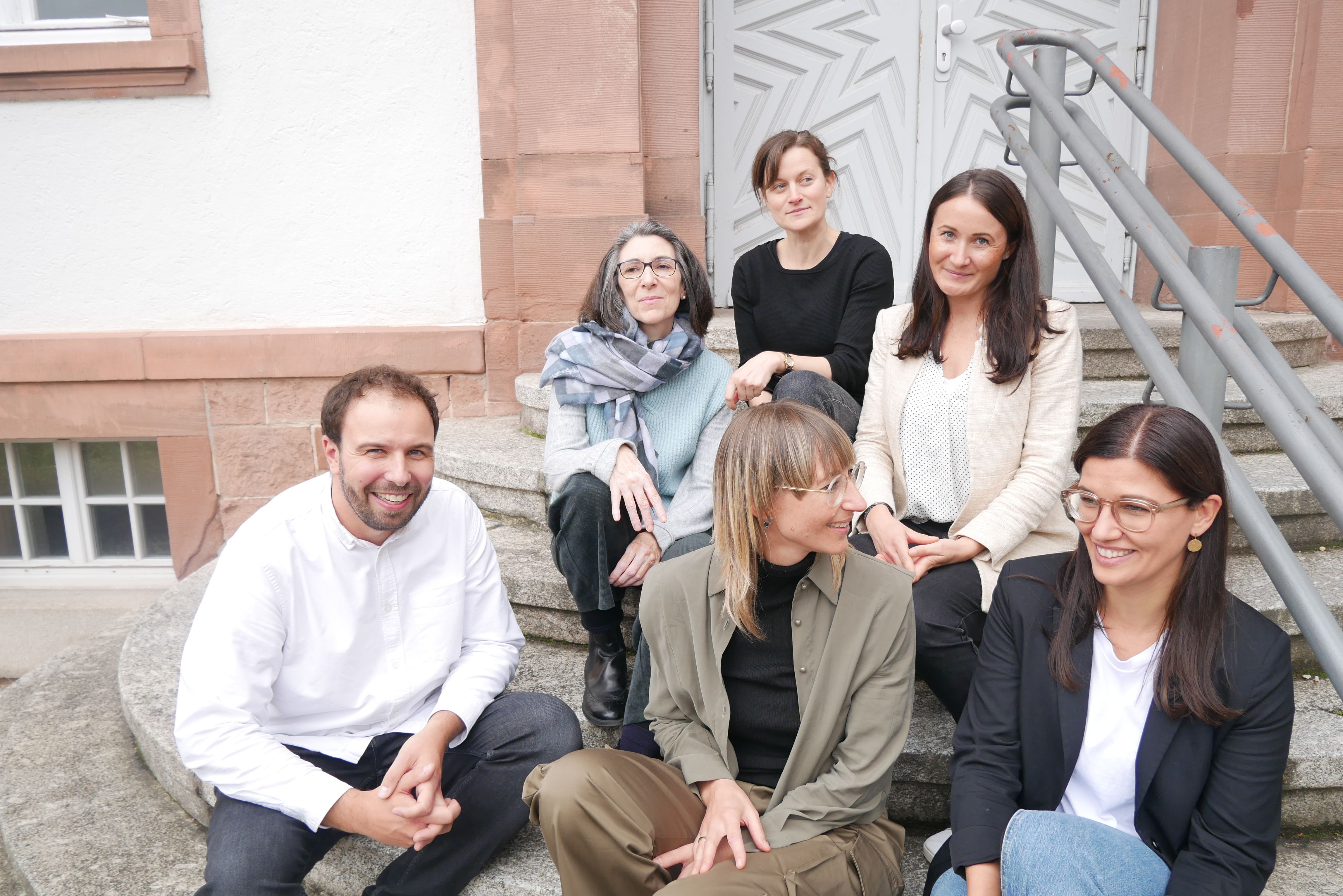 Die Ausbilder:innen der Fachrichtung Lernen sitzen auf der Treppe vor dem Eingang des Seminars.